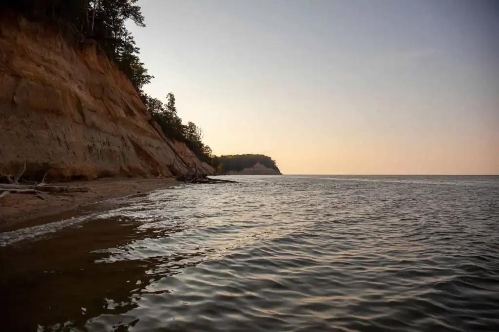Coastal cliffs beside water at sunset